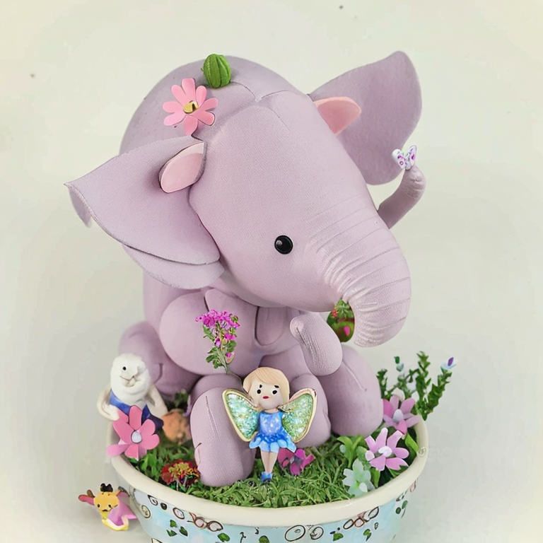 Fairy garden full of happy animals all dancing around a pink elephant in summer flowers.